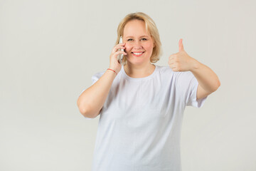 Wall Mural - beautiful young plump female in a white t-shirt with a phone in her hand