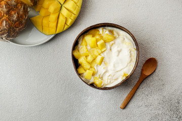 healthy breakfast consept, yogurt with fresh mango and pineapple in the coconut bowl