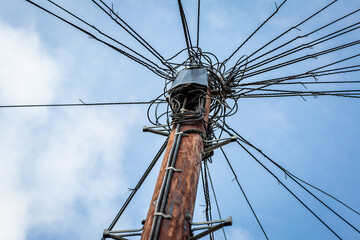 Old telegraph pole against a blue sky with junction boxes abd cables