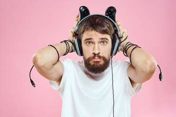 Man in headphones with joysticks in hands playing games lifestyle fun entertainment pink background