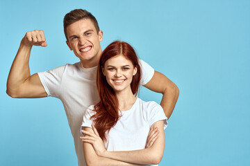 strong man showing arm muscles on blue background and young woman cropped view