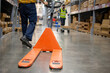 An employee is dragging a pallet truck in the warehouse.