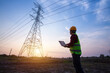© tong2530 - electrical engineer standing and watching at the electric power station to view the planning work by producing electricity at high voltage electricity poles in construction site