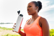 © Syda Productions - fitness, sport and healthy lifestyle concept - young african american woman drinking water from bottle outdoors