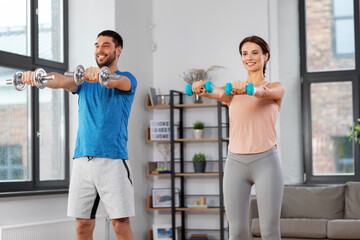 Poster - sport, fitness, lifestyle and people concept - smiling man and woman exercising with dumbbells at home