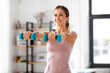 © Syda Productions - fitness, sport and healthy lifestyle concept - smiling young woman with dumbbells exercising at home