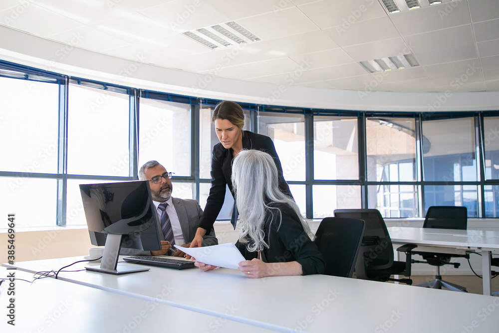 Company managers reporting to female boss. Businesspeople sitting at meeting table with holding paper and talking. Business discussion or teamwork concept - obrazy, fototapety, plakaty 