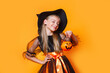 Cute girl in Halloween wicth costume on orange background