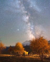 Milky Way in the sky over Mount Elbrus and orange autumn trees