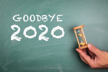 Wall Mural - GOODBYE 2020. Annual report, new year's expectations, planning and goals concept. Sandglass in hand