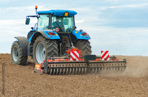 Cuadros en Lienzo Fresly plowed land and tractor with plough. Farming, nature.