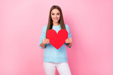 Wall Mural - Photo of pretty cute lady hold big paper red heart creative postcard inviting boyfriend romance date wear knitted blue sweater white trousers isolated pastel pink color background