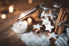 Christmas Still Life With Cinnamon Stars, Baking Ingredients. And Candlelight On A Wooden Background With Atmospheric Bokeh. Short Depth Of Field And Space For Text.