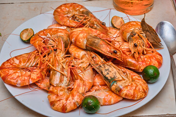 Red cooked prawns on a white plate with vegetables.