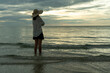 © Shisu_ka - Woman wearing a hat walks alone on an empty sandy beach at sunset. A lonely and depressed young woman stands on the sand of the beach on holiday.