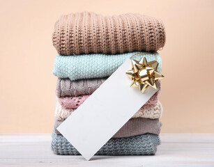 Wall Mural - Stack of knitted textured clothing with paper tag empty copy space.Winter clothes with empty blank for text.