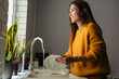 © Drobot Dean - Beautiful middle-aged woman smiling while washing dishes at home