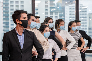 Multiethnic business group wearing face mask gesturing arm akimbo in new normal office