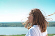 © Yulia Panova - beautiful woman with messy hair blown by wind looking at landscape. riverside country tranquil place. staycations and weekend travelling. sunny weather. happy cheerful woman.