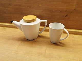 Teapot and white mug on a wooden table. Kitchenware concept