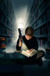 Junge beim Lesen im Dunkeln mit Taschenlampe in der Bibliothek