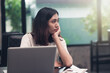 © palidachan - Unhappy Asian girlwith a laptop computer sitting in cafe, looking out of the window