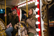 © Daniel - Two female friends riding on the carousel with horses at the winter festival
