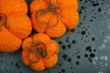 Bright Orange  Knitted Handmade Pumpkins On A Dark Spotted Background. Halloween Decoration.