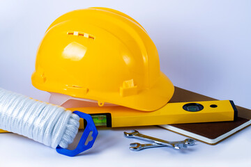 Safety First Concept: Safety Rope, notepad, level, metal wrenches and yellow helmet on the white table. Business and industry concept. Copy space for design.