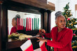 © Gerald Carter/Creative Flame - Senior Black woman setting up the Kwanzaa holiday setting and kinara with Christmas tree in background
