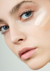 Wall Mural - Young woman applying three color samples of facial foundation cream at her face.