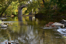 Eagle Creek Runs Through A Park In Indiana With An Arched Bridge Visible In The Background