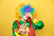Clown Standing Over Yellow Insolated Yellow Background Covering Eyes With Hands And Doing Stop Gesture With Sad And Fear Expression. Embarrassed And Negative Concept.