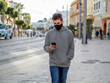 © David Martínez - Hombre joven con mascarilla usando su teléfono móvil por la calle