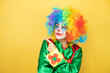 © Irene - Clown standing over yellow insolated yellow background serious pointing with hand and finger to the side