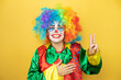 © Irene - Clown standing over yellow insolated yellow background smiling swearing with hand on chest and fingers up, making a loyalty promise oath