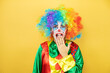 © Irene - Clown standing over yellow insolated yellow background with her hands over her mouth and surprised, looking side