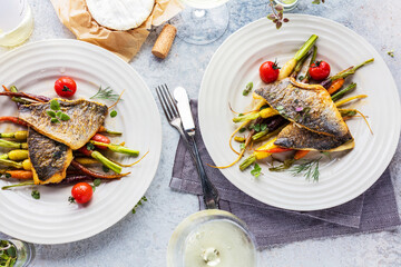  sea fish with rainbow carrot and wine     glasses on bright table. gourmet dissh