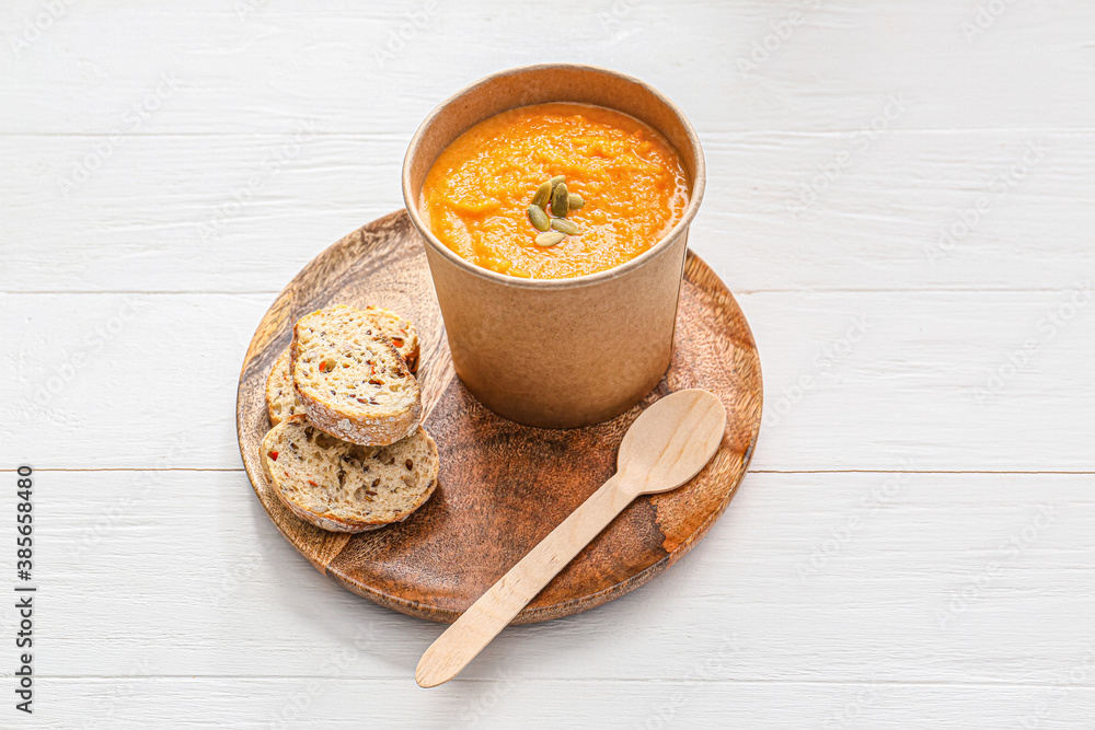 Tasty pumpkin cream soup in cup on table