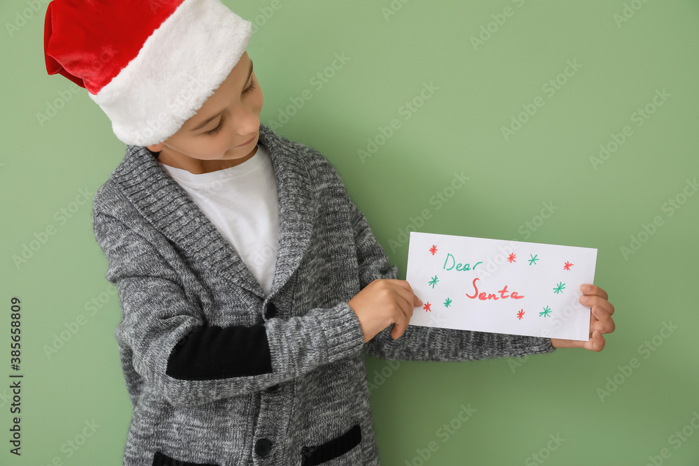 Little boy with letter to Santa on color background