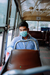 Business man wear mask travel by a bus transportation in Bangkok