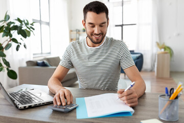 Poster - remote job and business concept - happy smiling man with papers, calculator and laptop computer working at home office