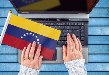 woman hands and flag of Venezuela on computer, laptop keyboard 