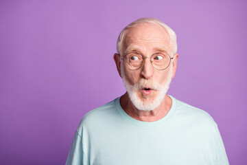 Portrait of surprised pensioner wear light blue t-shirt glasses open mouth empty space isolated on violet color background