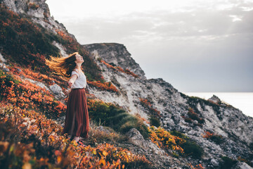 Woman walk in the autumn grass in mountains on vacation.