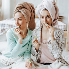 Two girls make homemade face and hair beauty masks. Cucumbers for the freshness of the skin around the eyes. Women take care of youthful skin