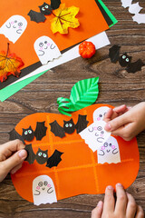 Wall Mural - Funny paper toy in the form of a Halloween pumpkin on a wooden table. Childrens art project, crafts, fun activities for kids.