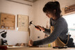 © Martina - A young female carpenter working as wood designer in a small carpentry workshop. Young business woman handcrafting a piece of timber and designing new house furniture. Entrepreneurs concept lifestyle