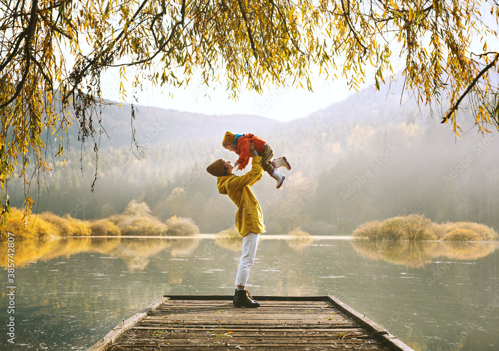 Family in nature background. Mother and child relaxing near by lake outdoors. - obrazy, fototapety, plakaty 