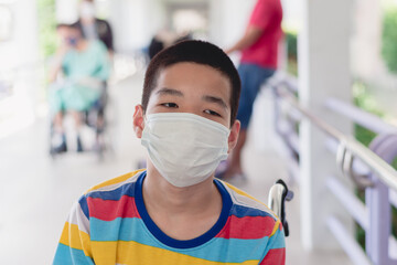 asian special child on wheelchair wearing a protection mask against pm 2.5 air pollution and flu cov